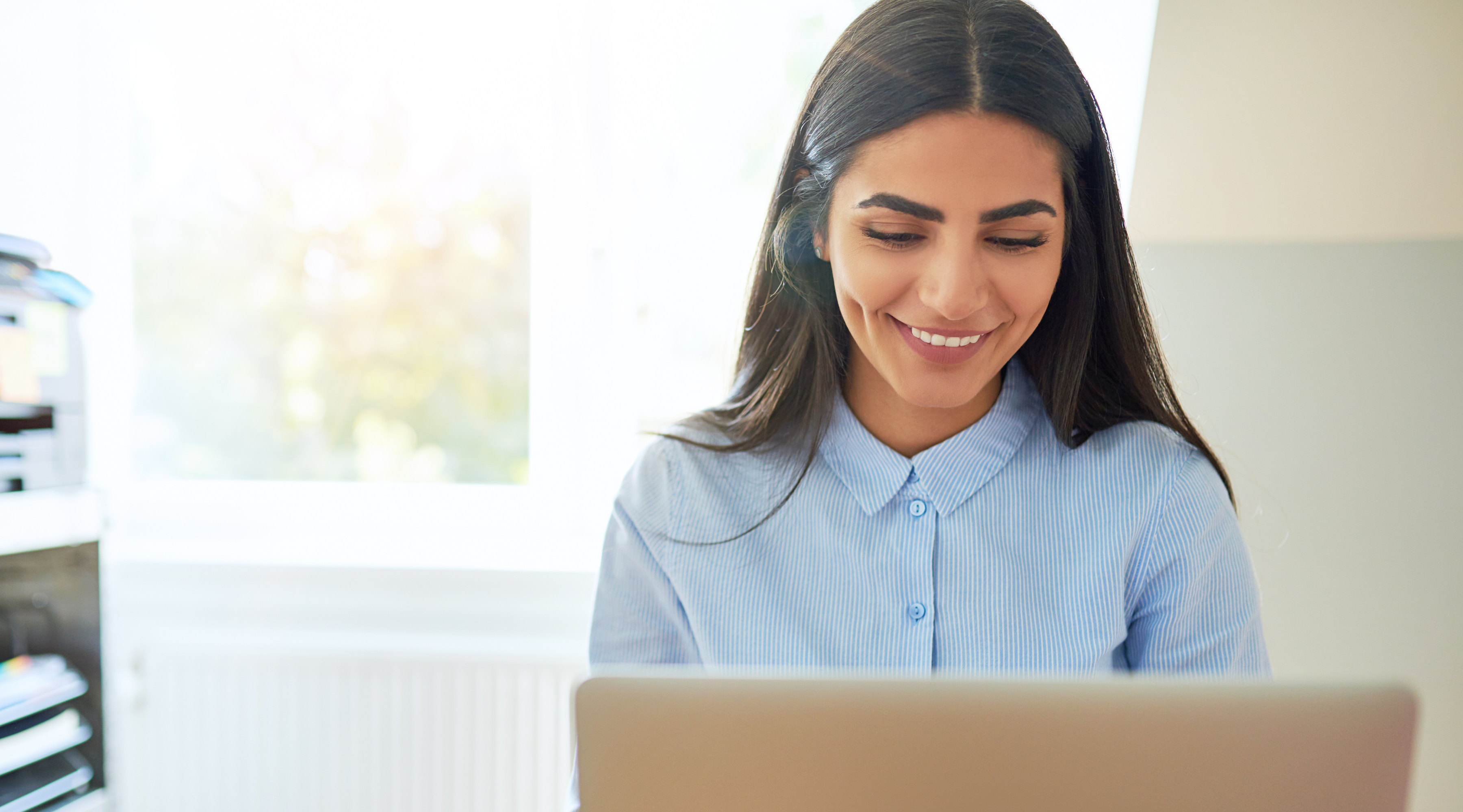 Photo of happy woman on computer - positive employee experience